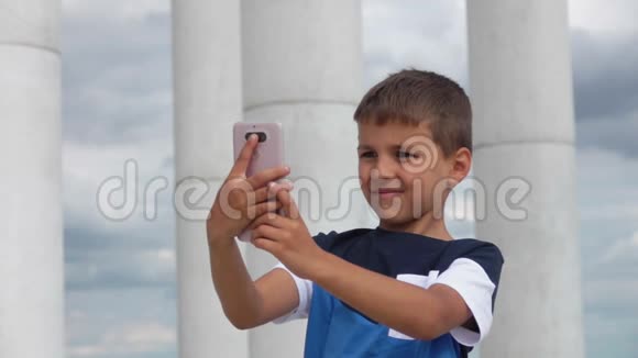 男孩在手机上对着天空和柱廊自拍视频的预览图