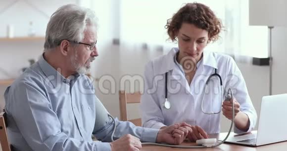 测量老年男性患者血压的女性医生视频的预览图