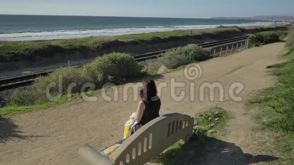 女人快乐美丽阳光明媚的夏日坐在海边的长凳上旅游假期退休生活方式概念视频的预览图