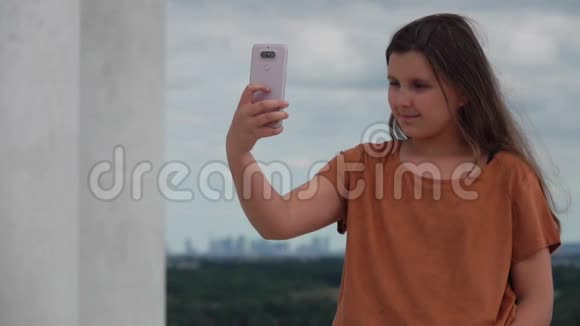 穿着棕色T恤的布鲁内特少女在手机上自拍视频的预览图