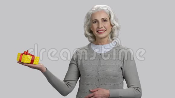 戴着灰色头发的老退休女士拿着礼品盒视频的预览图