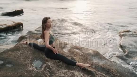 女士坐在岩石上的纵线与海洋视频的预览图