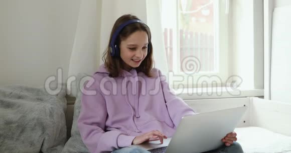 戴着耳机坐在床上的少女微笑视频的预览图