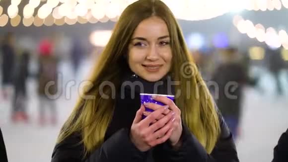 冬天有热饮的女孩站在溜冰场旁视频的预览图