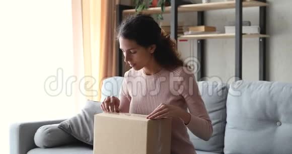 幸福的年轻女子在家拆包邮包视频的预览图
