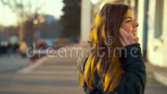 欢乐的女孩在日落时分在城市街道上打电话视频的预览图