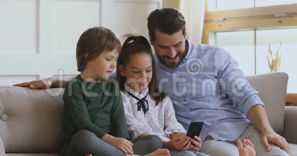 小女孩给弟弟和父亲看有趣的卡通片视频的预览图