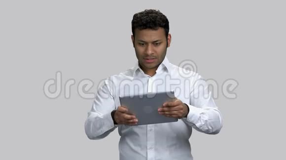 非常兴奋的深色皮肤的家伙在他的平板电脑上玩电子游戏视频的预览图