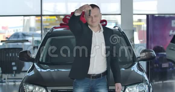 自信的白人商人吹嘘汽车钥匙和交叉手的肖像年轻的成功人士站在前面视频的预览图