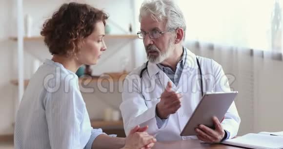 微笑的高级医生显示良好的测试结果握手的女性患者视频的预览图