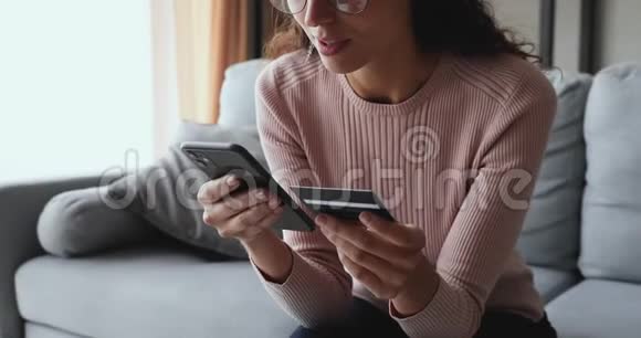 微笑年轻女性顾客使用智能手机持有信用卡视频的预览图