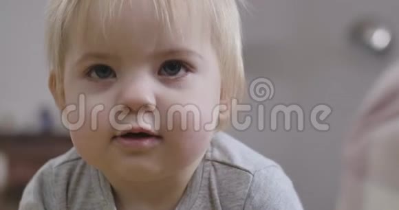 美丽的白种人女婴的特写脸灰色的眼睛和金色的头发张开嘴抬头看肖像视频的预览图