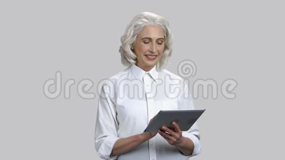快乐快乐的高级女士与平板电脑视频的预览图