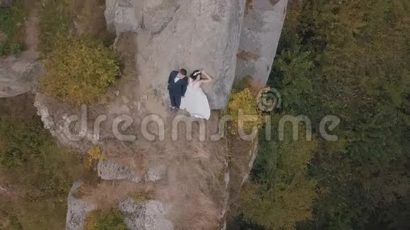 新婚夫妇站在山的高坡上新郎和新娘空中景观视频的预览图