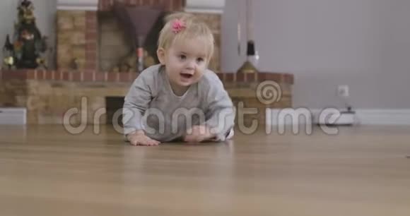 开朗的金发白种人女婴灰色的眼睛在地板上爬行到镜头可爱的孩子在家玩得开心视频的预览图