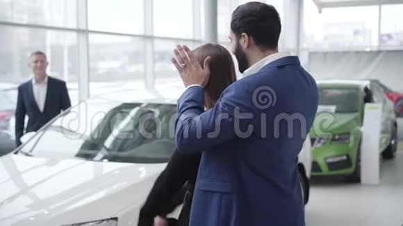 富有的中东商人打开了开朗的高加索女人的眼睛在经销商处展示了她的新白车视频的预览图