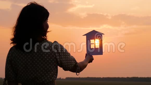 一个女人做梦拿着纸屋看着夕阳纸屋的剪影视频的预览图