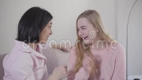 高加索女人和女孩坐在沙发上谈笑风生的肖像快乐的少年女儿视频的预览图