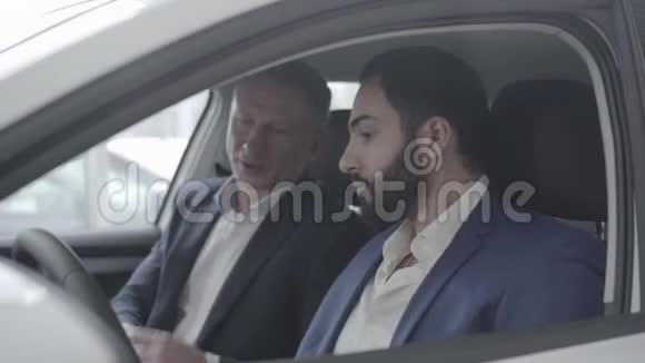 侧面看富有的中东男子与经销商在车成功人士选择车辆的特写视频的预览图