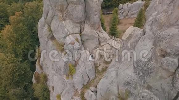 新婚夫妇站在山的高坡上新郎和新娘空中景观视频的预览图