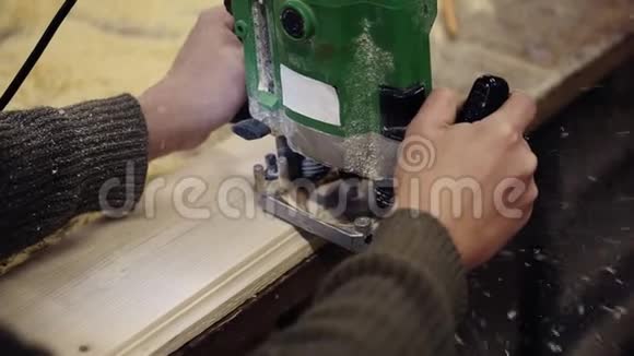 在木车间用手工打磨机进行抛光的工匠手的肩膀上的脚印视频的预览图