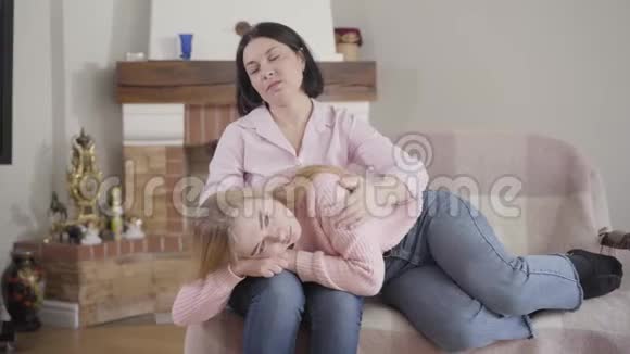 一幅令人沮丧的白人少女躺在母亲膝盖上分享她的问题的肖像聪明的黑发女人劝她视频的预览图