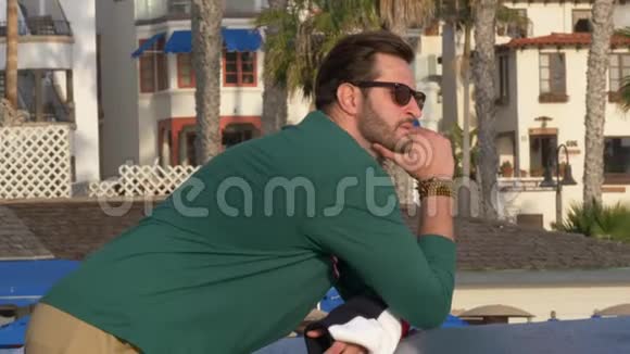 一个英俊的年轻人一个穿着海军蓝衬衫短裤和眼镜的男人在加州的圣克莱门特海岸闲逛视频的预览图