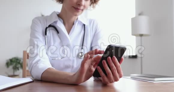 女性医生使用智能手机应用程序咨询远程病人特写视频的预览图