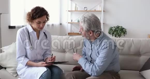 女医生检查老年病人坐在沙发上探望祖父视频的预览图