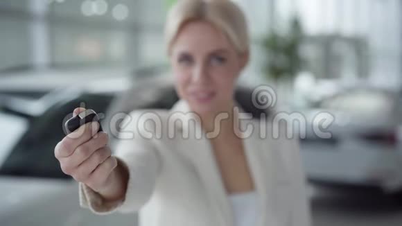 特写女性白种人手打开汽车钥匙模糊的金发女人在后台对着镜头微笑成功视频的预览图