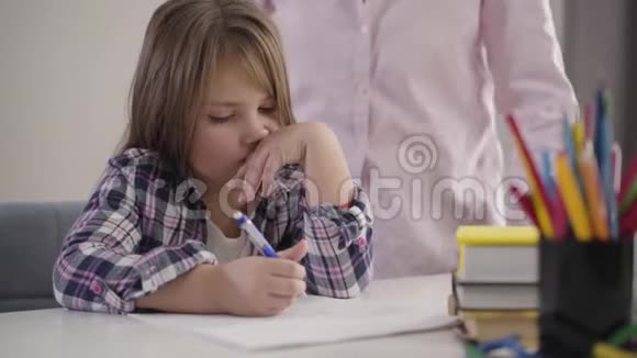 疲惫的白种人女孩坐在桌子旁写字的特写肖像无法辨认的女人在握手视频的预览图