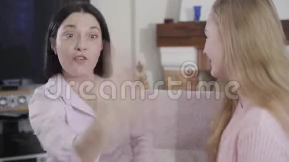 一位年轻的黑发白种人女人和金发女孩有感情地交谈妈妈和女儿在一起视频的预览图