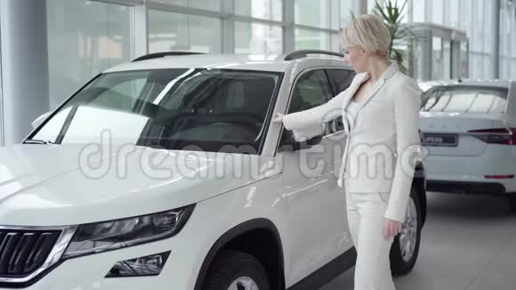 自信的金发白种人女人在汽车经销商和交叉手接触新车的肖像成功视频的预览图