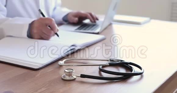 年纪较大的医生坐在医疗室的桌子上用听诊器检查视频的预览图