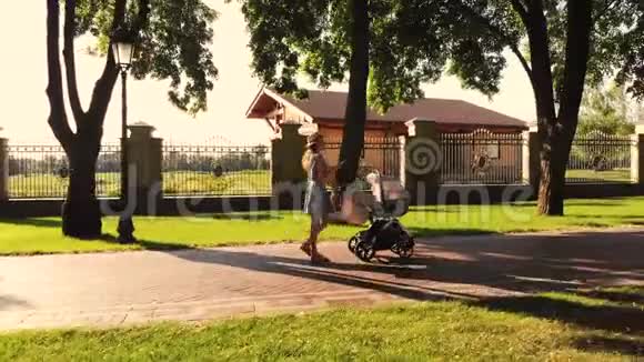 侧视现代母亲推着婴儿马车在手机上打字视频的预览图