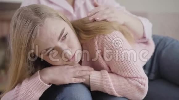 躺在母亲的膝盖上和说话哭泣的白种人女孩的特写镜头十几岁的女儿和视频的预览图