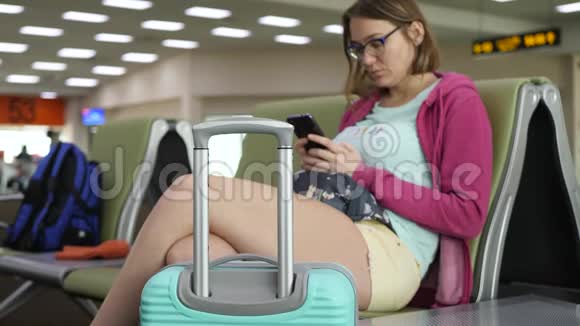 年轻游客女性在机场出发时使用智能手机视频的预览图