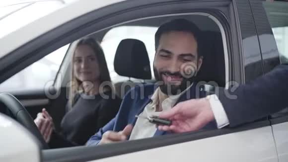 微笑的中东男人从经销商那里拿着车钥匙递给兴奋的妻子的肖像感恩的配偶视频的预览图