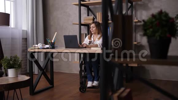 在家工作时坐轮椅伸展身体的女人视频的预览图