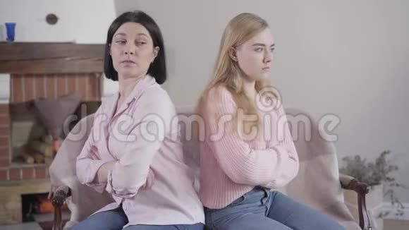 镜头接近黑发白种人女人和金发女孩背靠背坐在沙发上母亲和视频的预览图