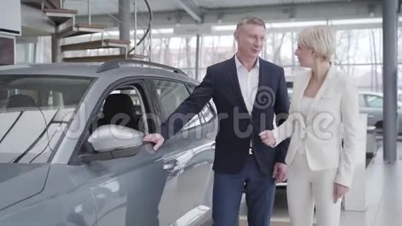 自信的高加索女商人选择汽车在经销商微笑经销商咨询客户在展厅商人视频的预览图