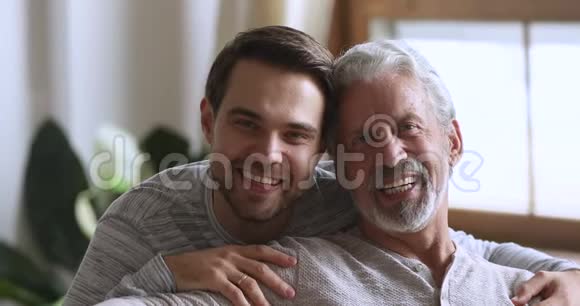 英俊的年轻人拥抱快乐的老人的肩膀视频的预览图
