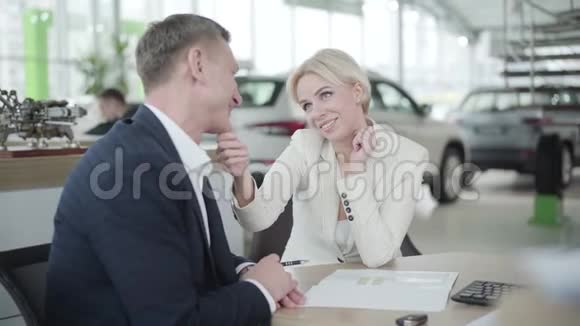 陈列室中年轻女子与汽车经销商调情的肖像自信的白种人女商人穿着优雅的白色西装视频的预览图