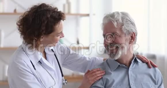 关爱善良的女医生拥抱令人放心的快乐老年病人视频的预览图