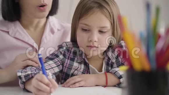 一位浓黑肤色的黑黑肤色女孩在练习本上写着自己无法辨认的母亲在练习本上口述视频的预览图