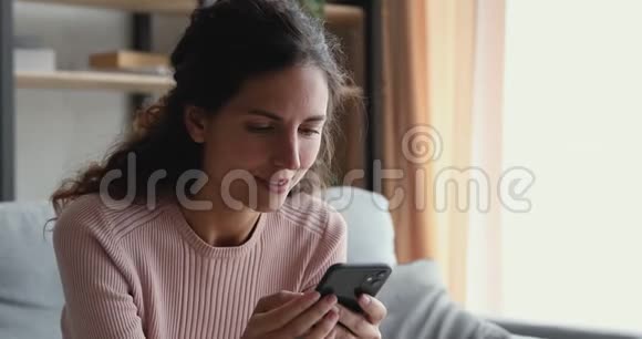 微笑的千禧一代女人在看智能手机的视频故事视频的预览图