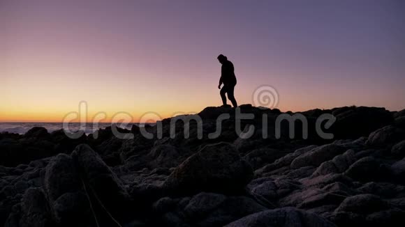 在海边的岩石上练习放松技巧的男人视频的预览图