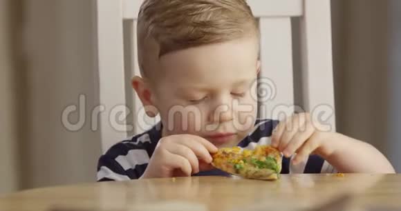 小男孩吃比萨饼享受品味和微笑的肖像拍摄红相机视频的预览图