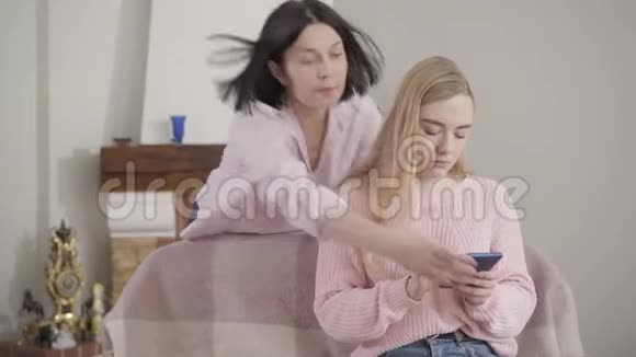 一名成年黑发白人女子拿走了女儿的智能手机妈妈在家责骂年轻少女视频的预览图