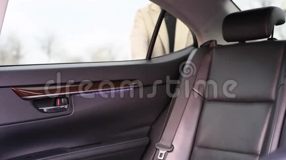 漂亮的年轻女子打开车门坐上出租车使用智能手机视频的预览图